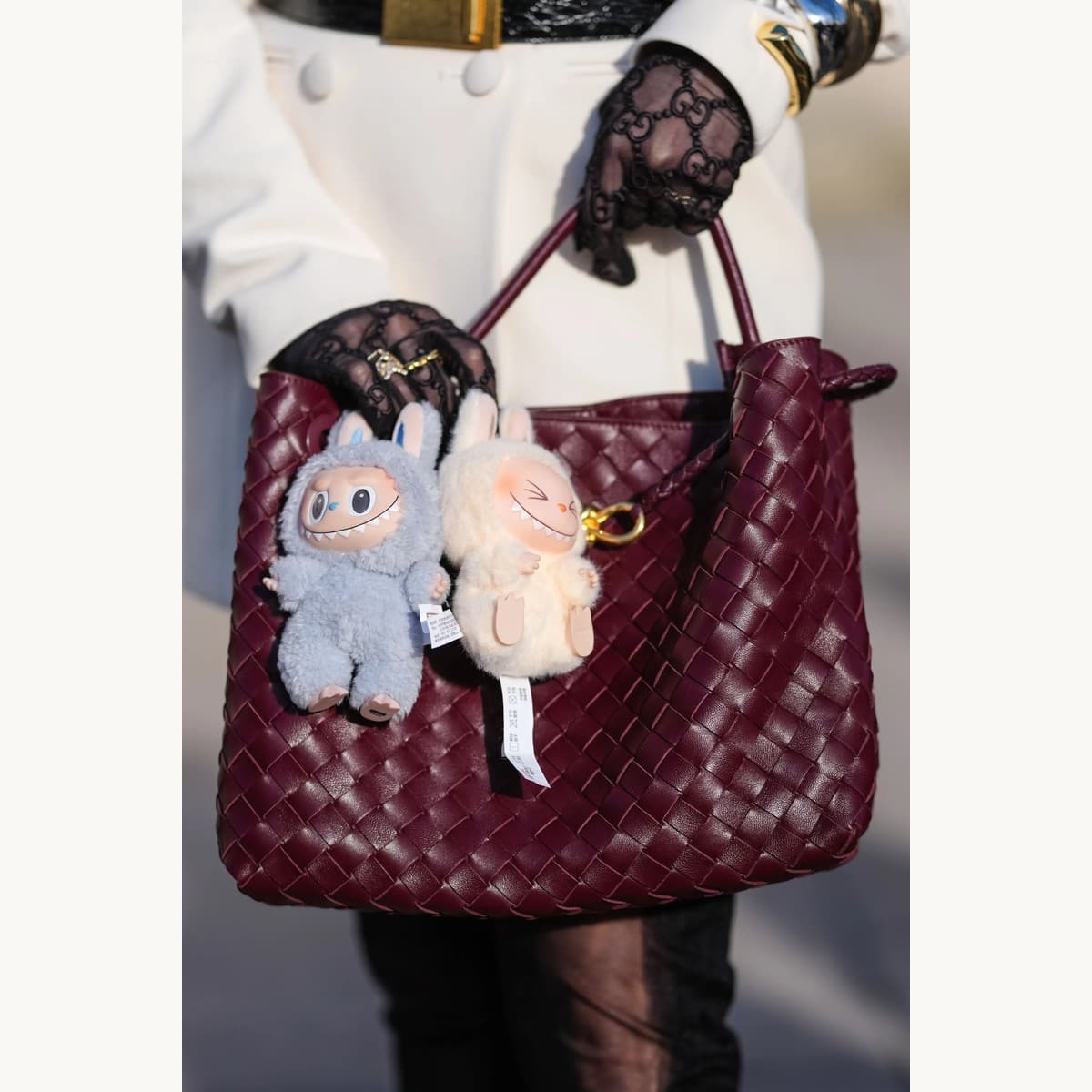 Labubu plush charm clipped to a designer handbag
